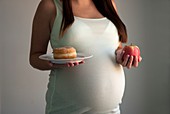 Pregnant teenager with a doughnut and an apple