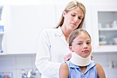 Doctor applying neck support to girl