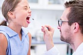 Doctor taking a swab from a girl's mouth