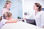 Medical receptionist smiling towards woman