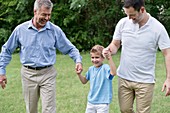 Grandfather, father and boy holding hands