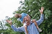 Grandfather carrying grandson on shoulders