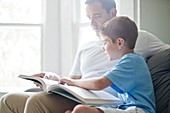 Boy reading book with his father
