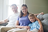 Boy sitting on sofa with his mother and father, portrait