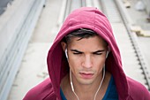 Young man wearing ear phones and hooded top