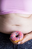 Woman holding doughnut in front of belly