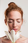 Woman smelling white lily with eyes closed
