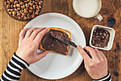 Woman spreading chocolate hazelnut spread on bread