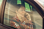 Worried woman talking on mobile phone in car