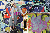 Blonde Frau in grauem Pulli und Rock vor Graffiti
