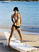 A young, short-haired woman on a beach wearing a bikini