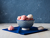 Pink and white meringues in a blue bowl