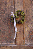 Small heart-shaped wreath of ivy berries with ribbon on doorknob