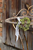 Heart-shaped wreath of ivy berries with ribbon on rusty metal frame