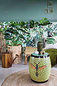 Ceramic stool with bee motif in front of jungle-patterned wallpaper