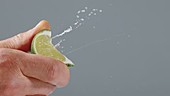 Person squeezing lime wedge, slow motion