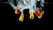 Peppers falling in water, slow motion