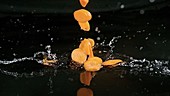 Carrot slices falling in water, slow motion