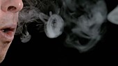 Person blowing smoke rings, slow motion