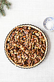 An unbaked caramel nut tart with sea salt in a baking tin (top view)