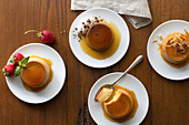 Assorted flavored individually plated flans on a rustic wood surface