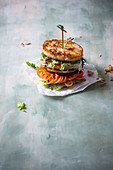 An Asian style burger with tofu, grilled pineapple and vegetable spirals a sticky rice bun (vegan)