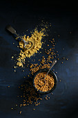 Mustard seeds and mustard powder on a dark background (top view)
