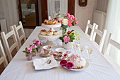 Dome cake, sparkling wine and roses on table set for afternoon coffee