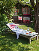 Sun lounger with cushions outside wooden cabin in garden