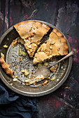 Two pieces of apple pie with almonds in a vintage baking dish (top view)