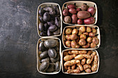 Variety of raw uncooked organic potatoes different kind and colors red, yellow, purple in market baskets