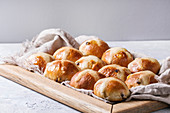Homemade Easter traditional hot cross buns on wooden tray with textile over white texture background