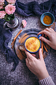 Woman drinking golden milk turmeric latte served in a blue cup