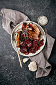 Grilled pork ribs in thick barbeque sauce garnished with red cabbage and beets braised in red wine sauce