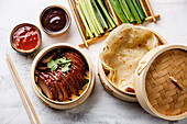 Sliced Peking Duck in bamboo steamer served with fresh cucumber, green onions, cilantro and roasted wheaten chinese pancakes with sauce Hoysin