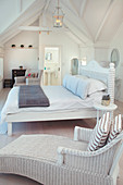 Wicker armchair and bed in white attic bedroom