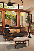 Baroque sofa and upholstered footstool in front of open, arched terrace doors