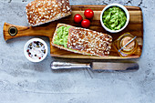 Wooden cutting board with homemade delicious avocado sandwiches over concrete textured background