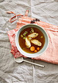 Semolina dumpling soup with carrots and peas