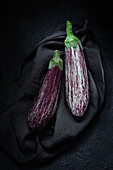 Two aubergines on a black cloth