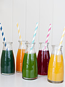 Individual jars of fresh pressed juices with straws (spirulina, orange carrot turmeric, spinach, beet and lemon ginger)