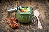 Cream of spinach soup with egg and crispy bacon in a jar