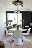 Designer chairs at round table in dining room with black accent wall