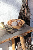 A sheep bell and bars of soap in a terracotta bowl on a wooden bench
