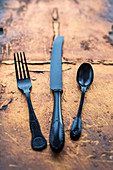 Black vintage knife fork and spoon on a copper slate