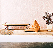 Camp bed and a cognac-colored beanbag on a sandy floor