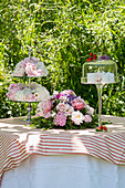 Romantischer Tisch im Garten mit Blumenschmuck und Tortenfuß