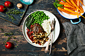 A slow cooked beef joint with red wine and mushroom sauce, mashed potatoes and peas