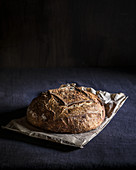 Round bread loaf on paper bag and dark fabric background