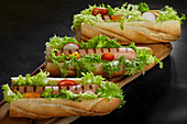 Baguettes with salad, grilled sausages, tomatoes and radishes